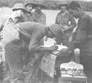 Signing the registration book of the Red Cross clubmobile when it visited the men advancing on Metz.