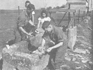 These GI's wash some of the dust of battle from their clothes under the supervision of two French girls.