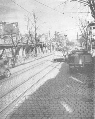 Third Army vehicles move down the streets of another captured town.