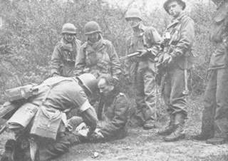 Captured Nazi officer is treated by medics of the 90th.